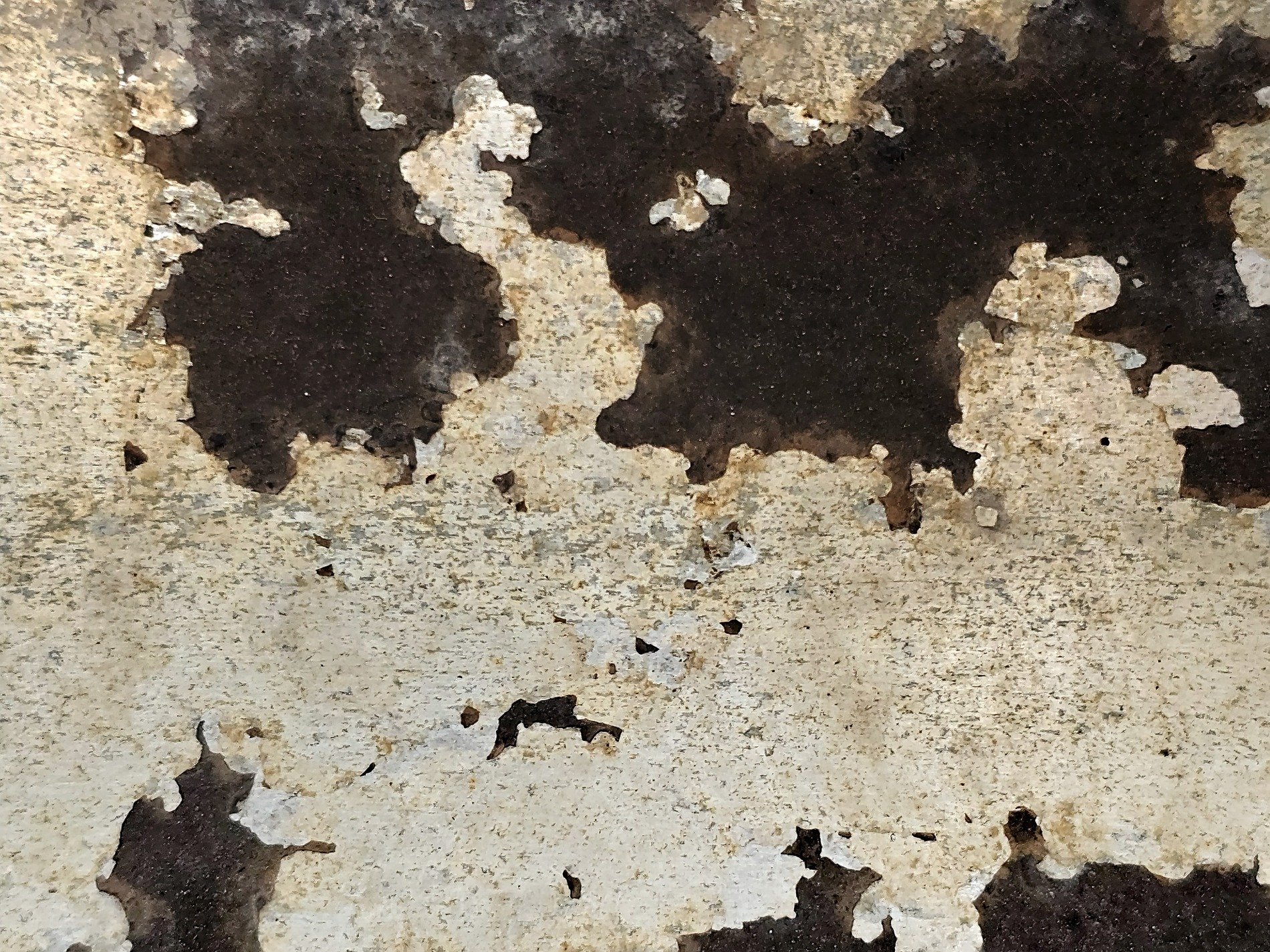 White paint flakes away, dark metal shows through the cracks, time peels back the layers