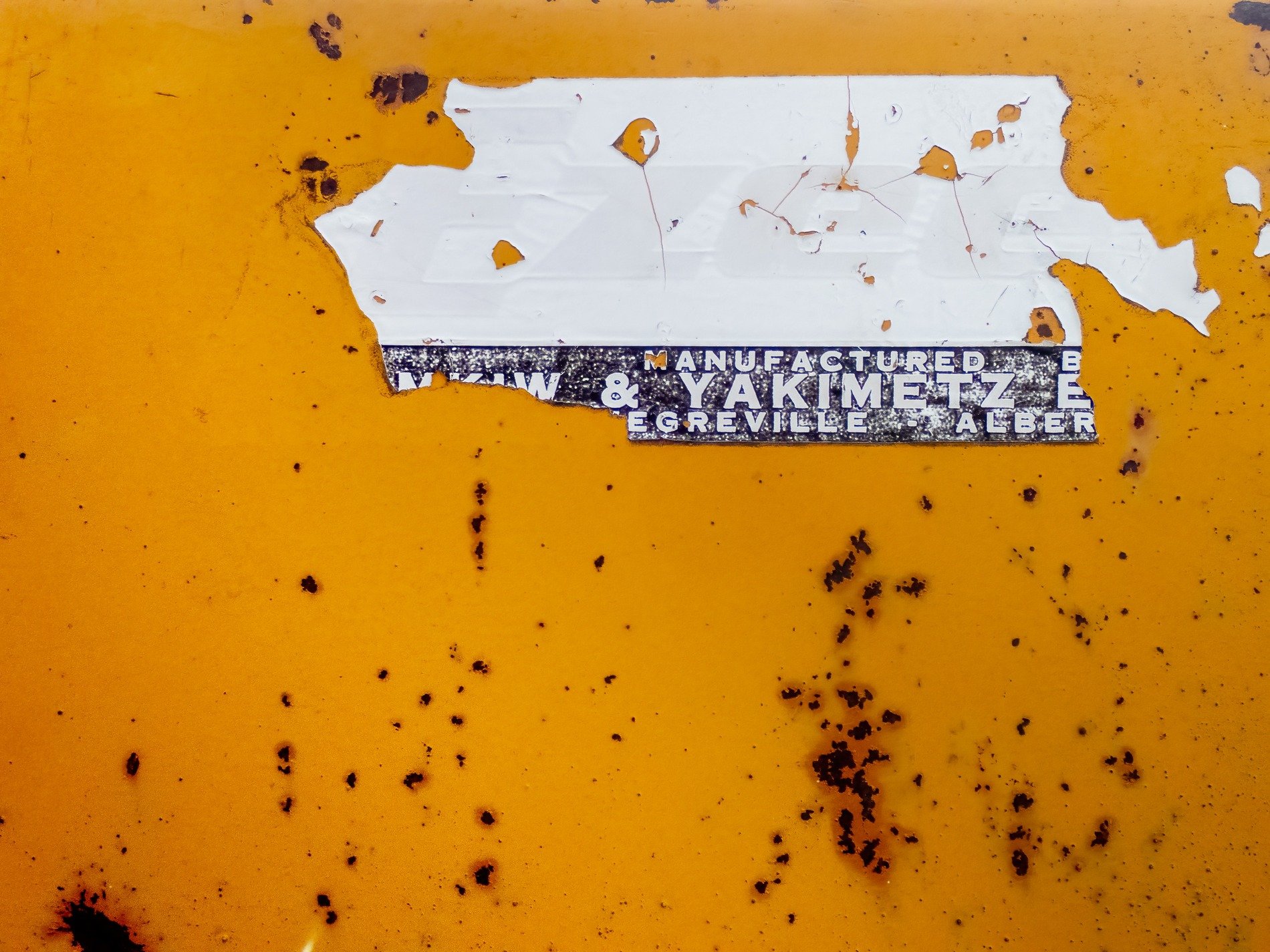 Yellow fields meet white, faded labels peel away, dark spots mark the skin