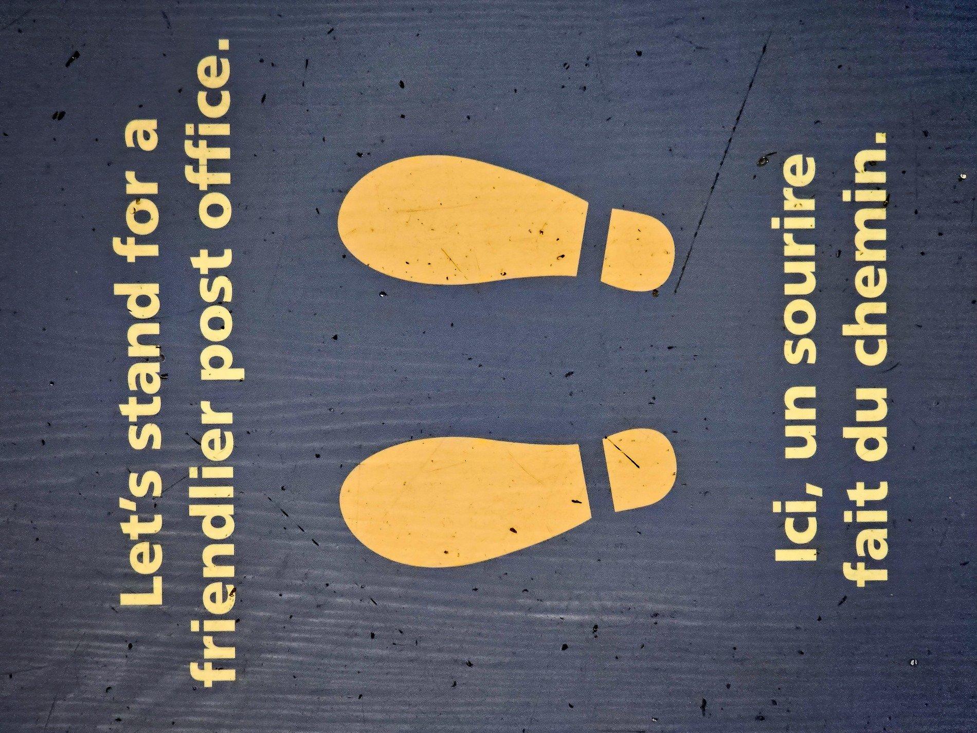Yellow footprints wait, friendly words on scuffed up blue, patience marks the spot