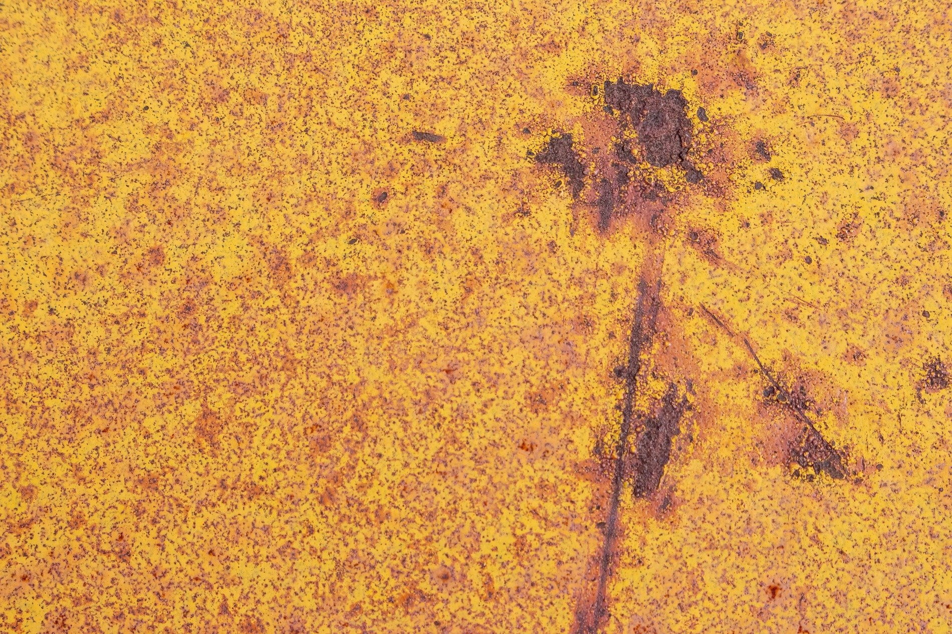 Yellow paint decays, iron oxide spreads its reach, dark scars mar the field