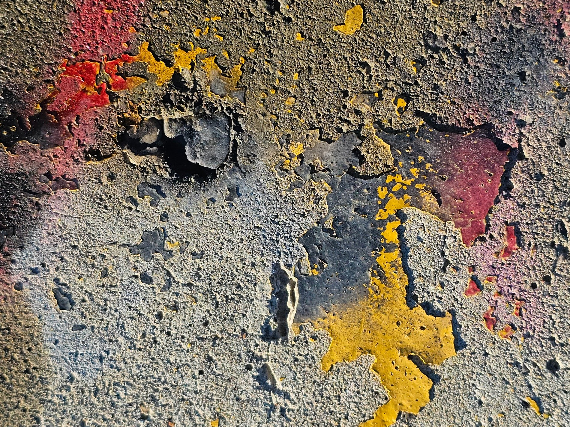 Yellow paint peels back, grey concrete shows through the gaps, red stains the corner