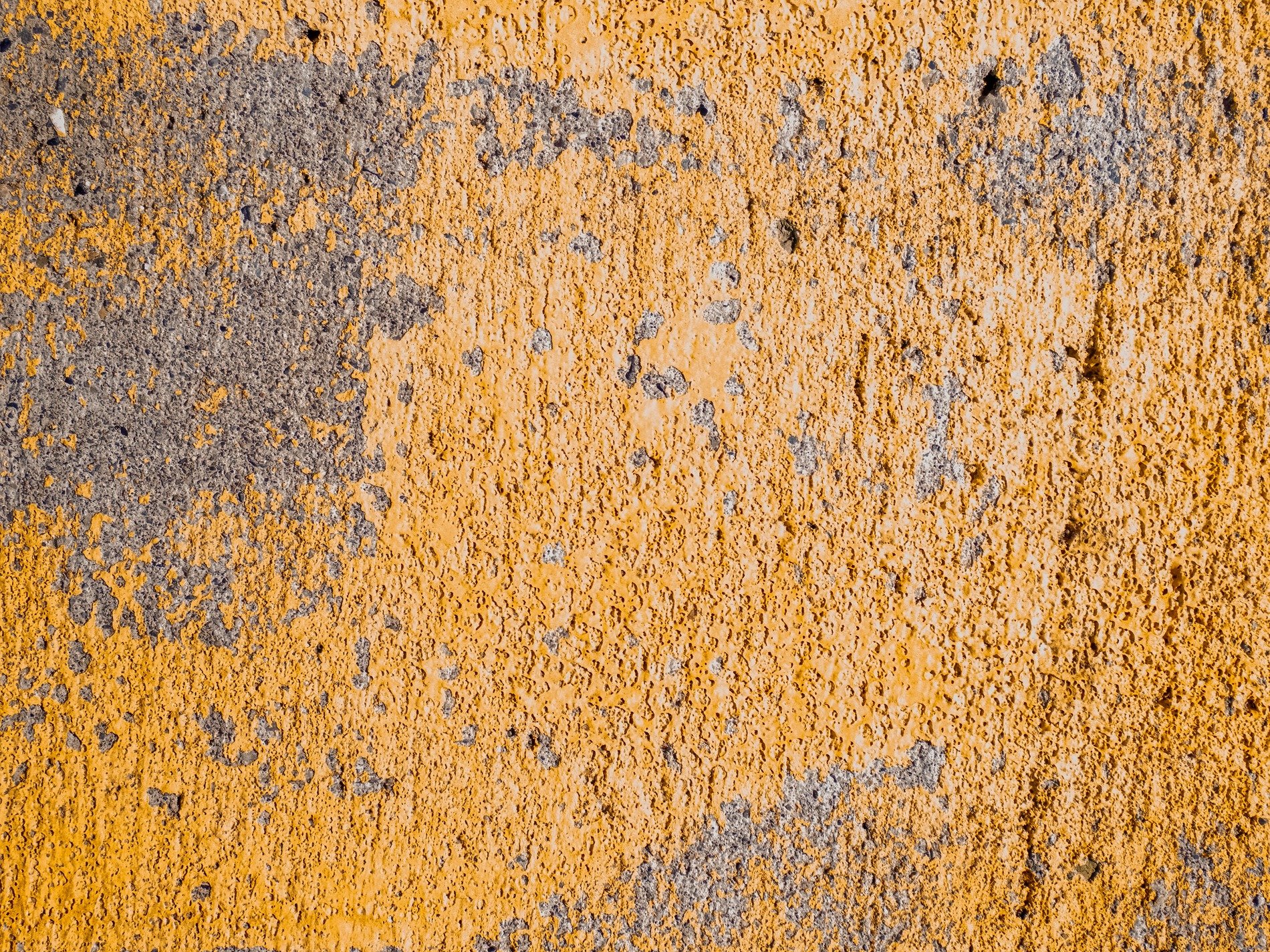 Yellow paint wears thin, rough grey stone hides underneath, time scrapes at the edge