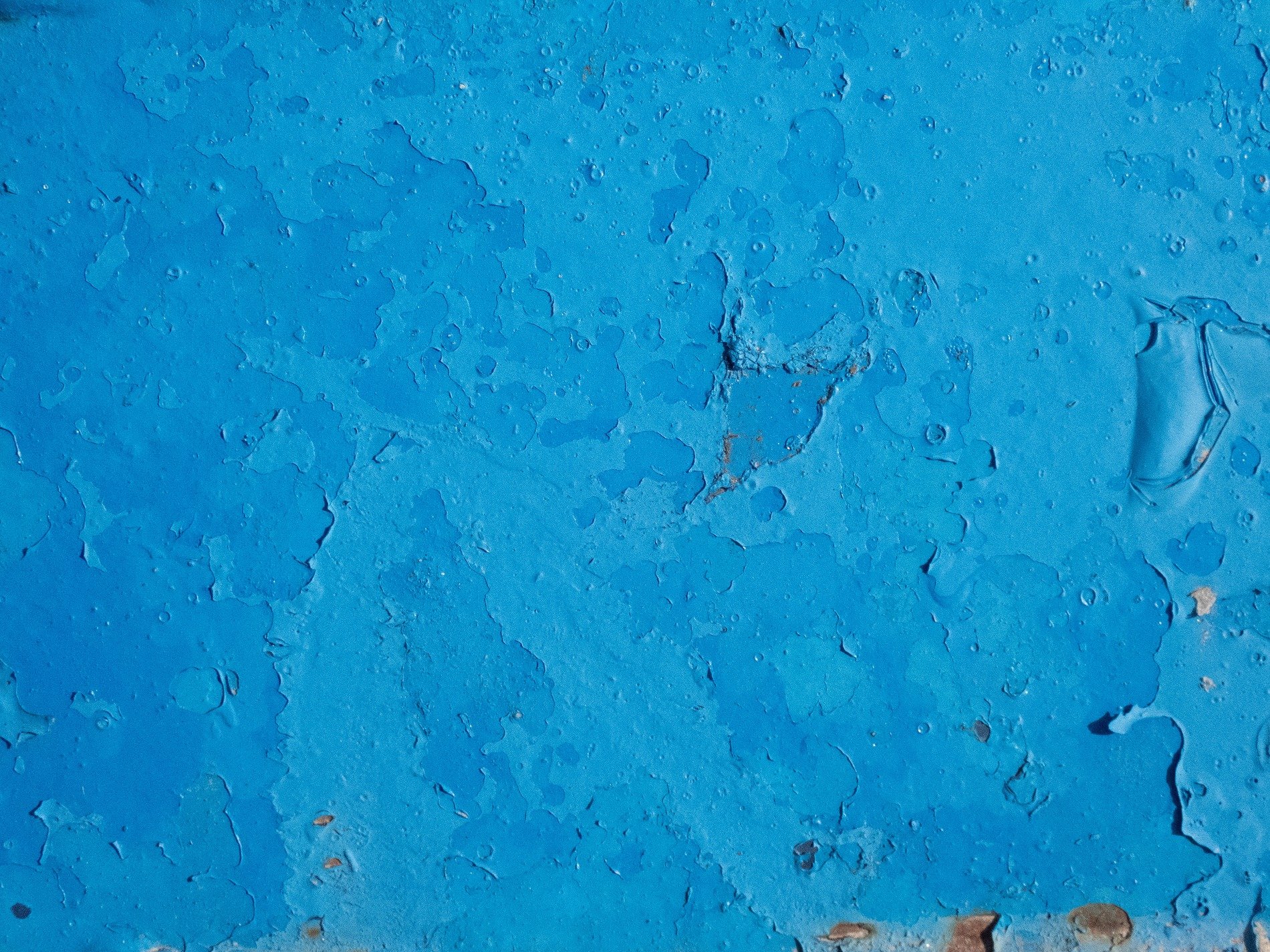 Blue layers chip away, weathered skin flakes from metal, time strips the surface