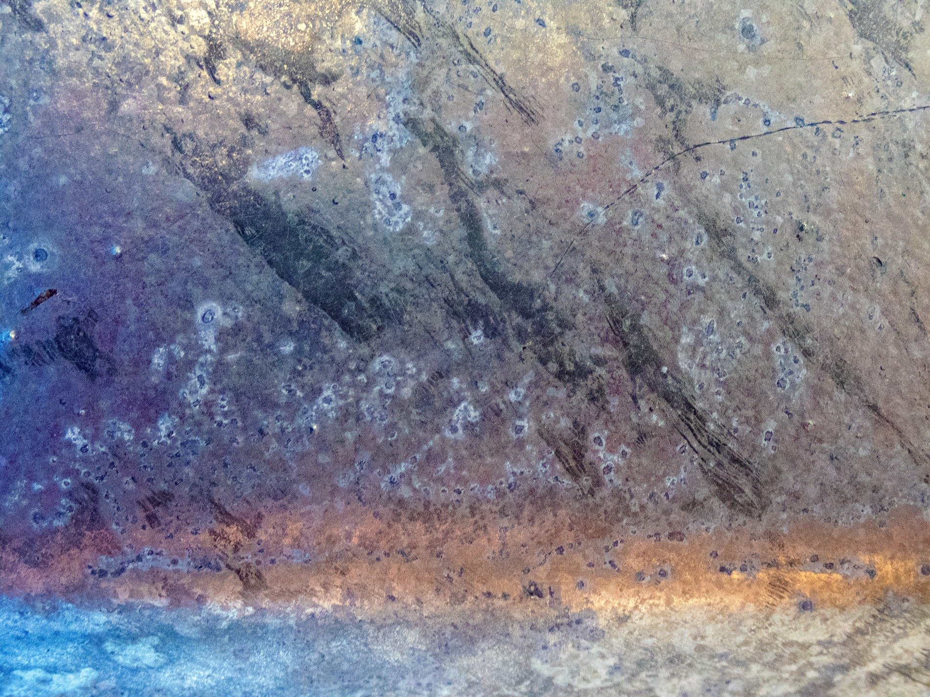 Blue metal scarred, heat blooms across the surface, time leaves spotted marks