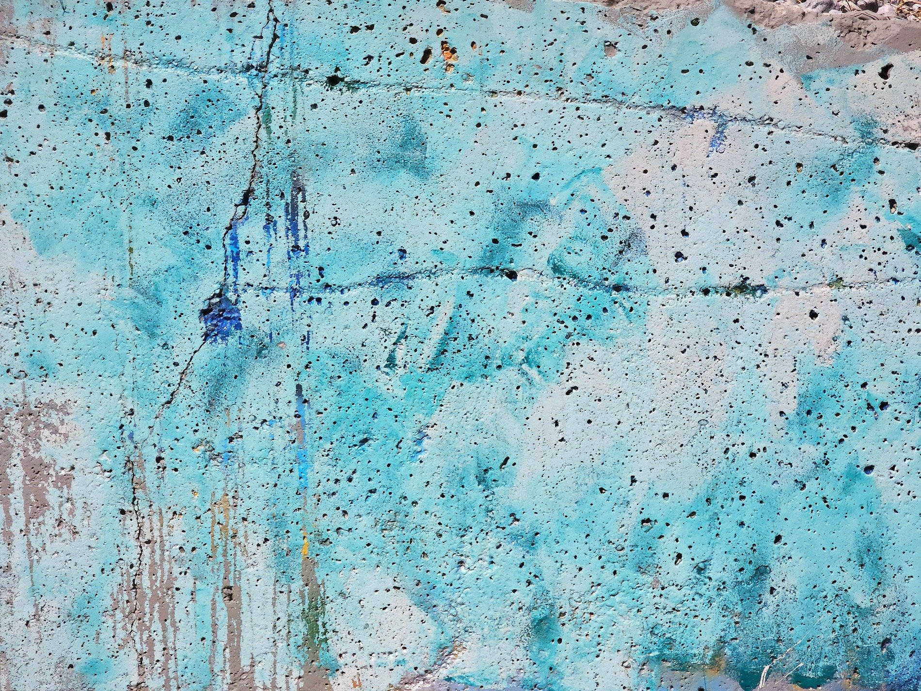Blue paint coats the stone, jagged cracks divide the face, porous shadows wait
