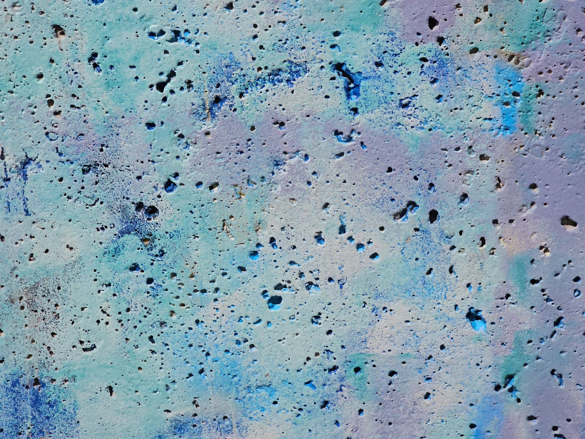 Blue paint masks the stone, pockmarks dot the rough surface, colors blend in light