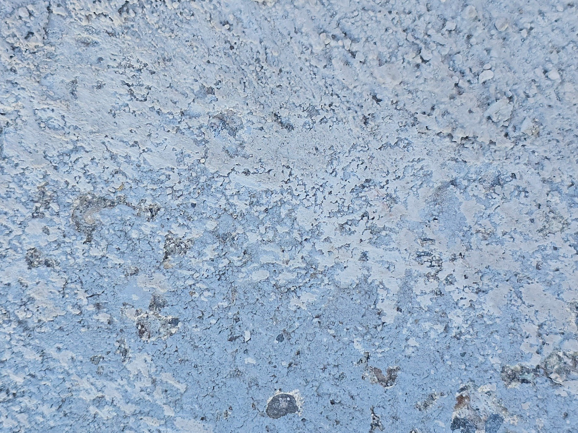 Blue paint wears away, rough concrete hides underneath, textures carved by time