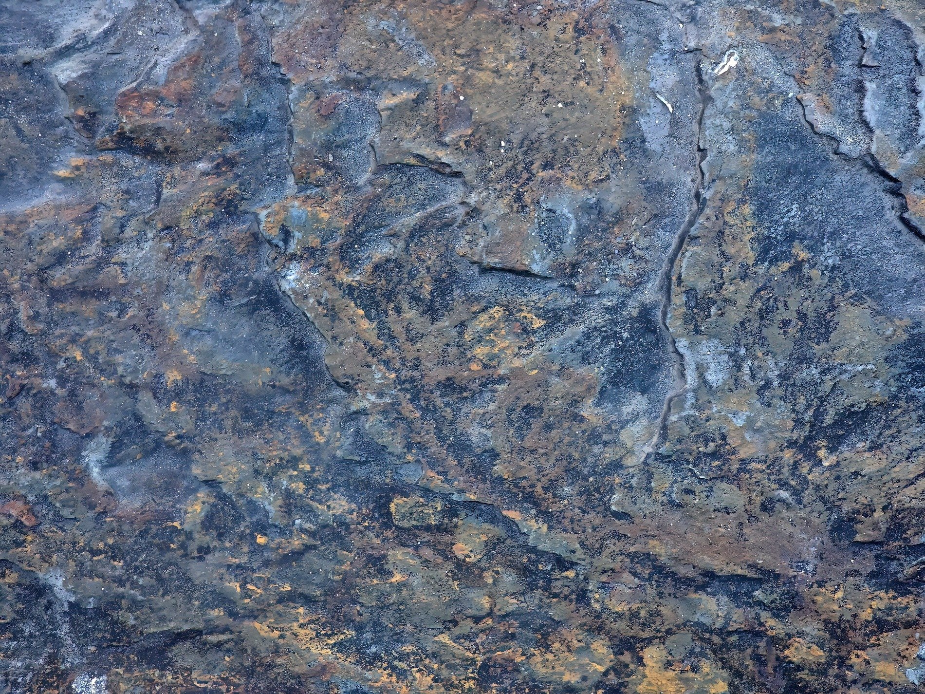 Blue shadows on stone, orange veins through the grey rock, ancient layers rest