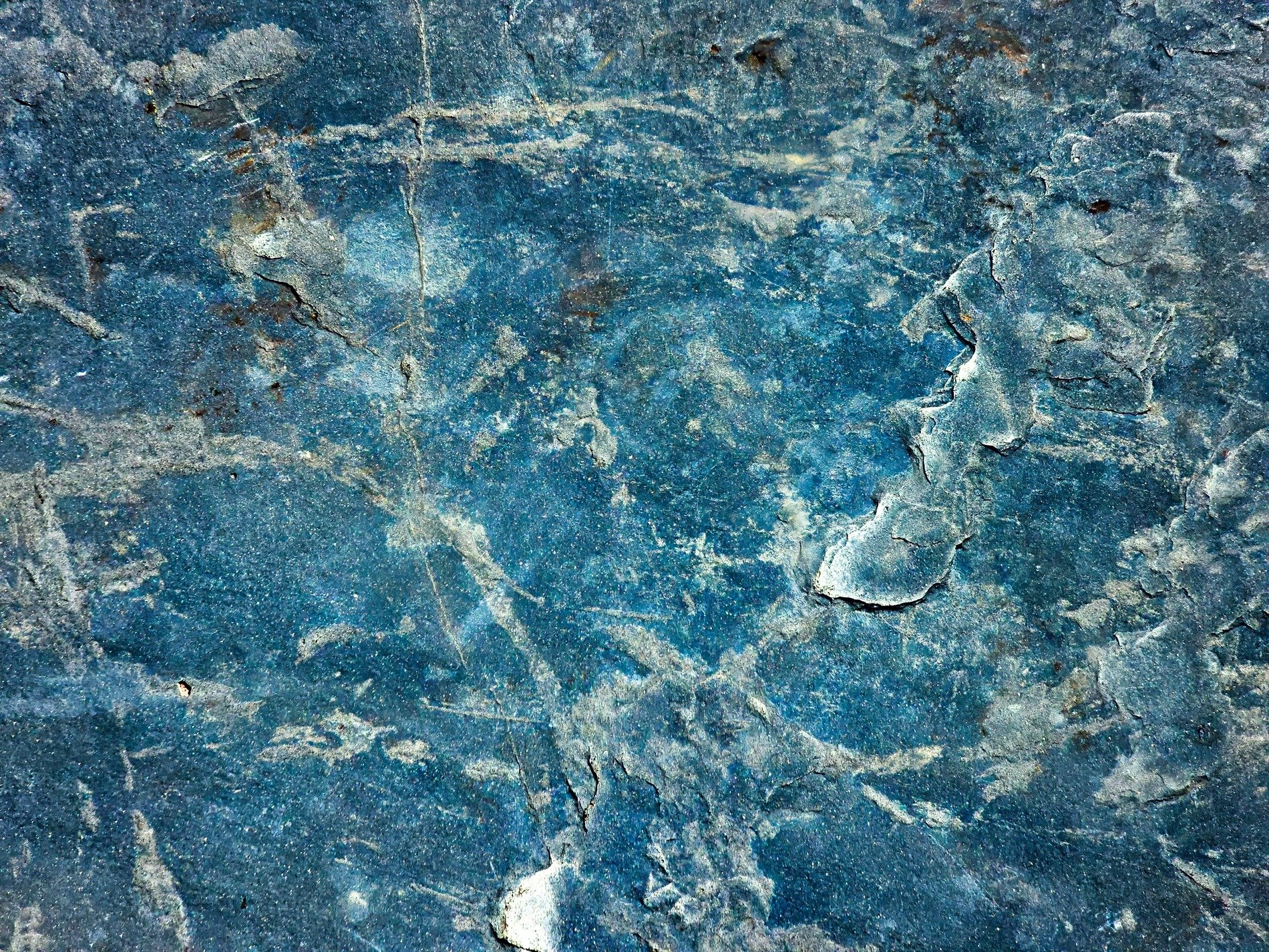 Blue stone deeply scarred, jagged veins cut through the rock, ancient surface stays