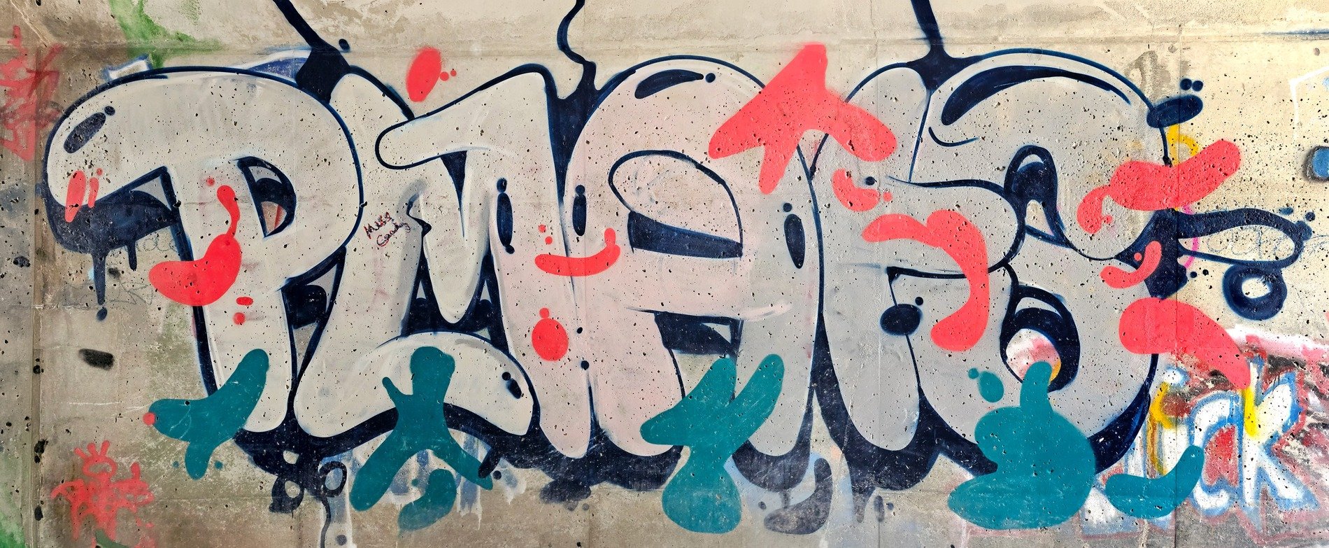 Bright paint on stone, bold letters flow through the gray, urban colors bloom