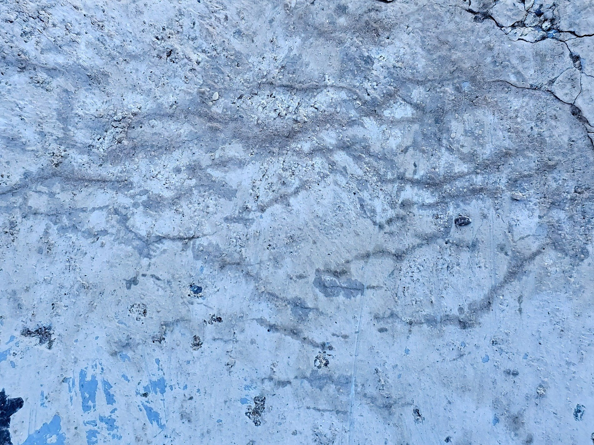 Frozen blue cement, rippled stains trace ancient lines, surface starts to break