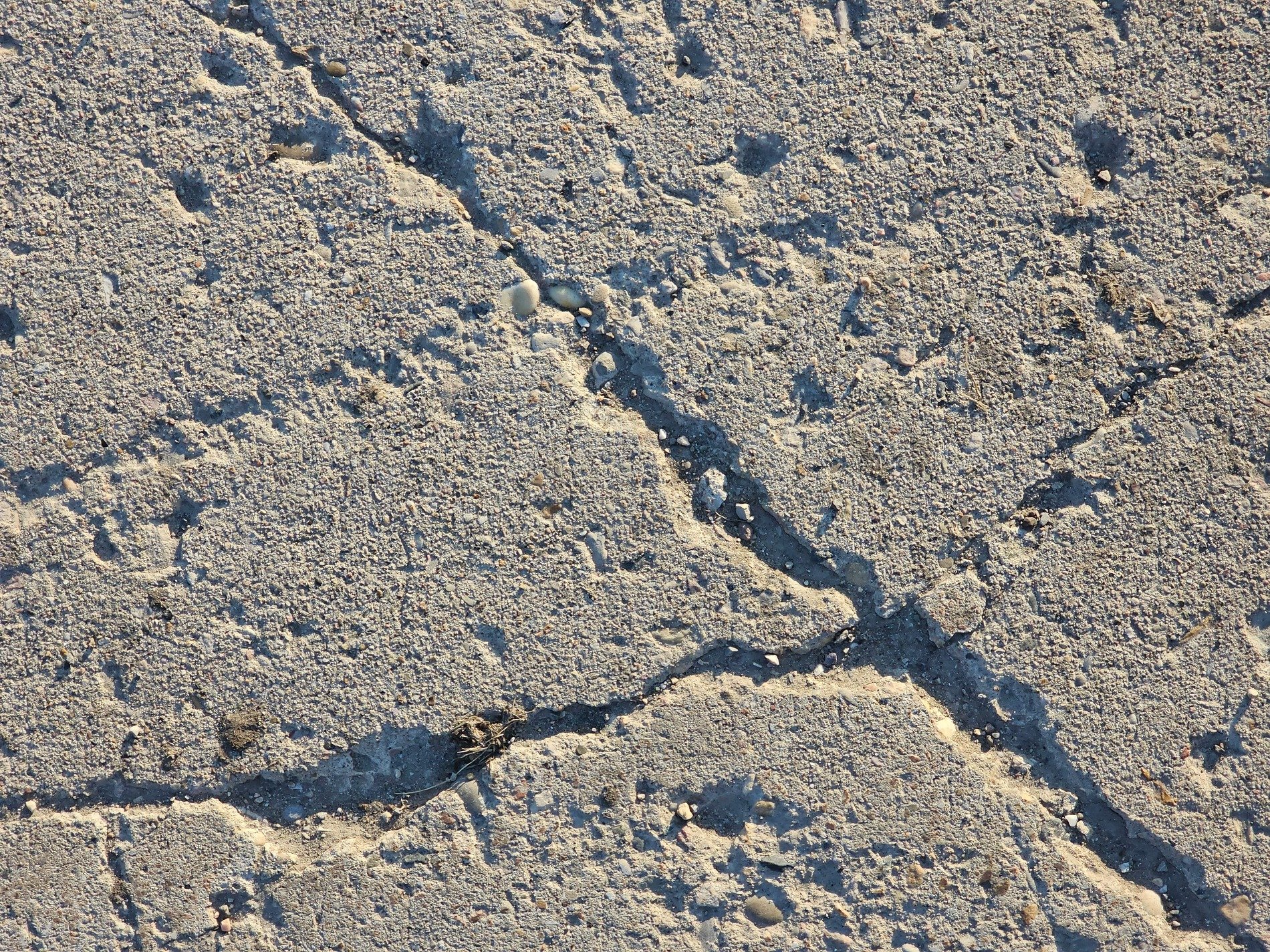 Grey slab splits apart, deep cracks mar the weathered face, grit and shadow meet