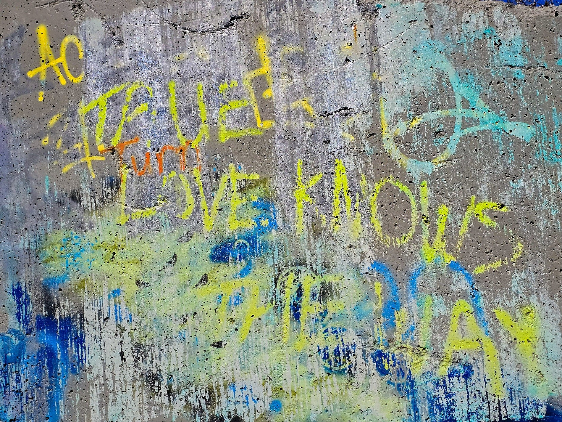 Grey wall stands so still, yellow paint speaks of the way, blue drips on the stone