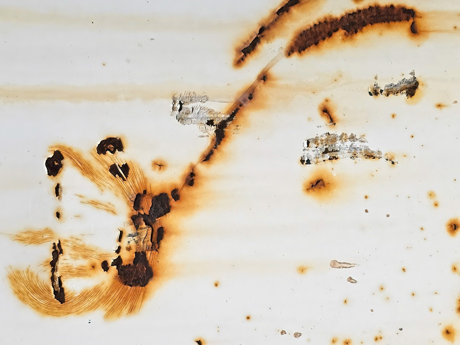 Iron meets the air, rust blooms on a field of white, slow decay takes hold