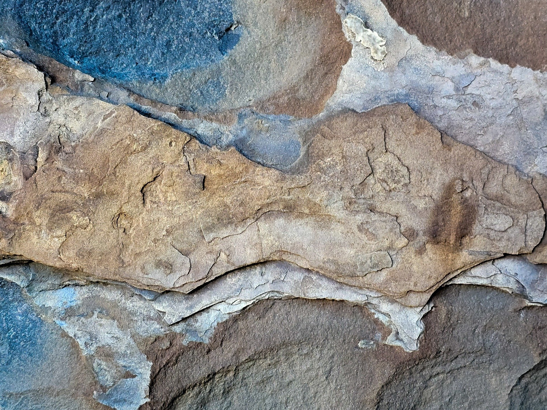 Layered ancient rock, shadow falls on dusty blue, time etched in the stone