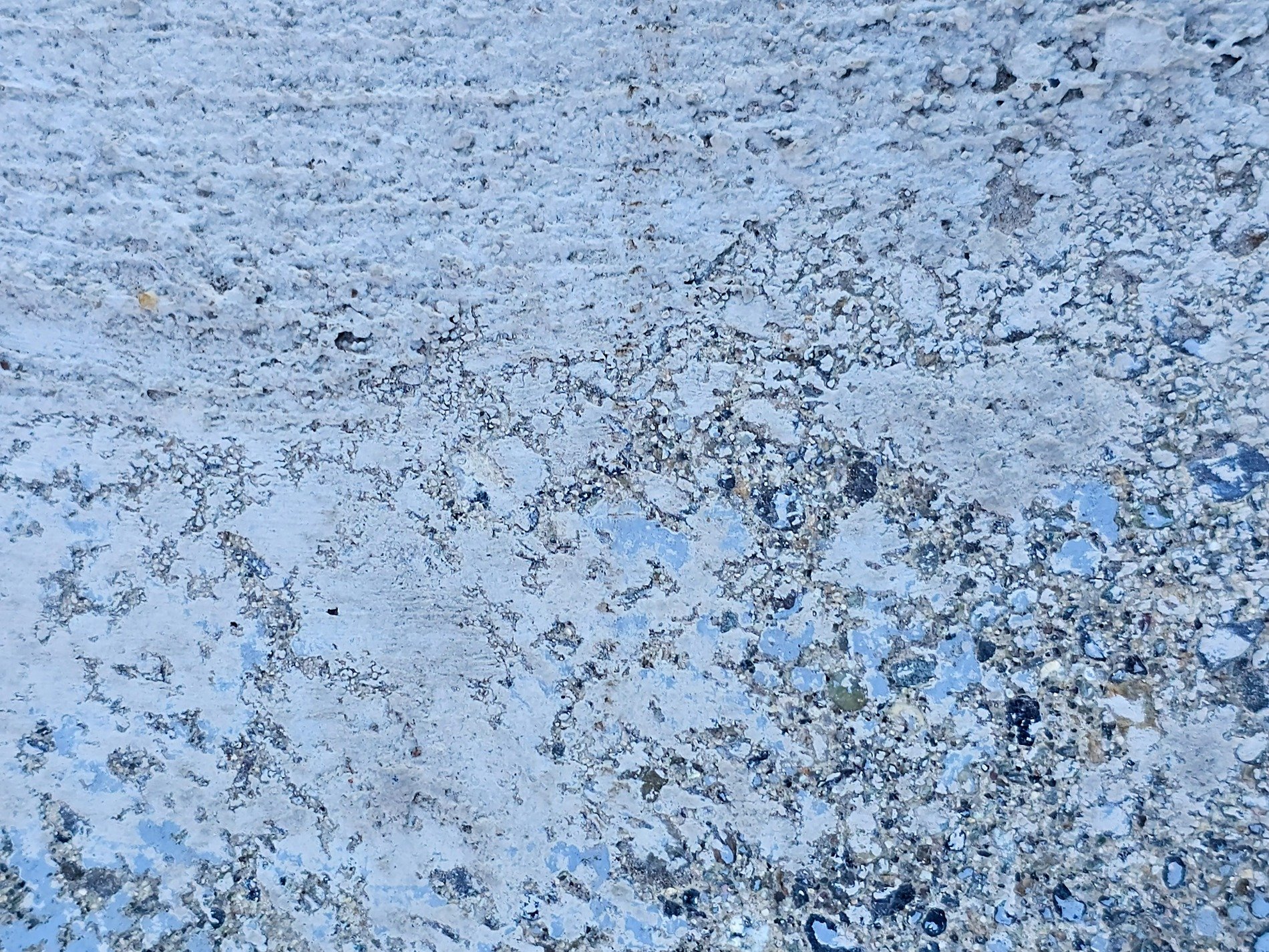 Pale blue paint fades out, rough concrete grit shows through now, time marks the surface
