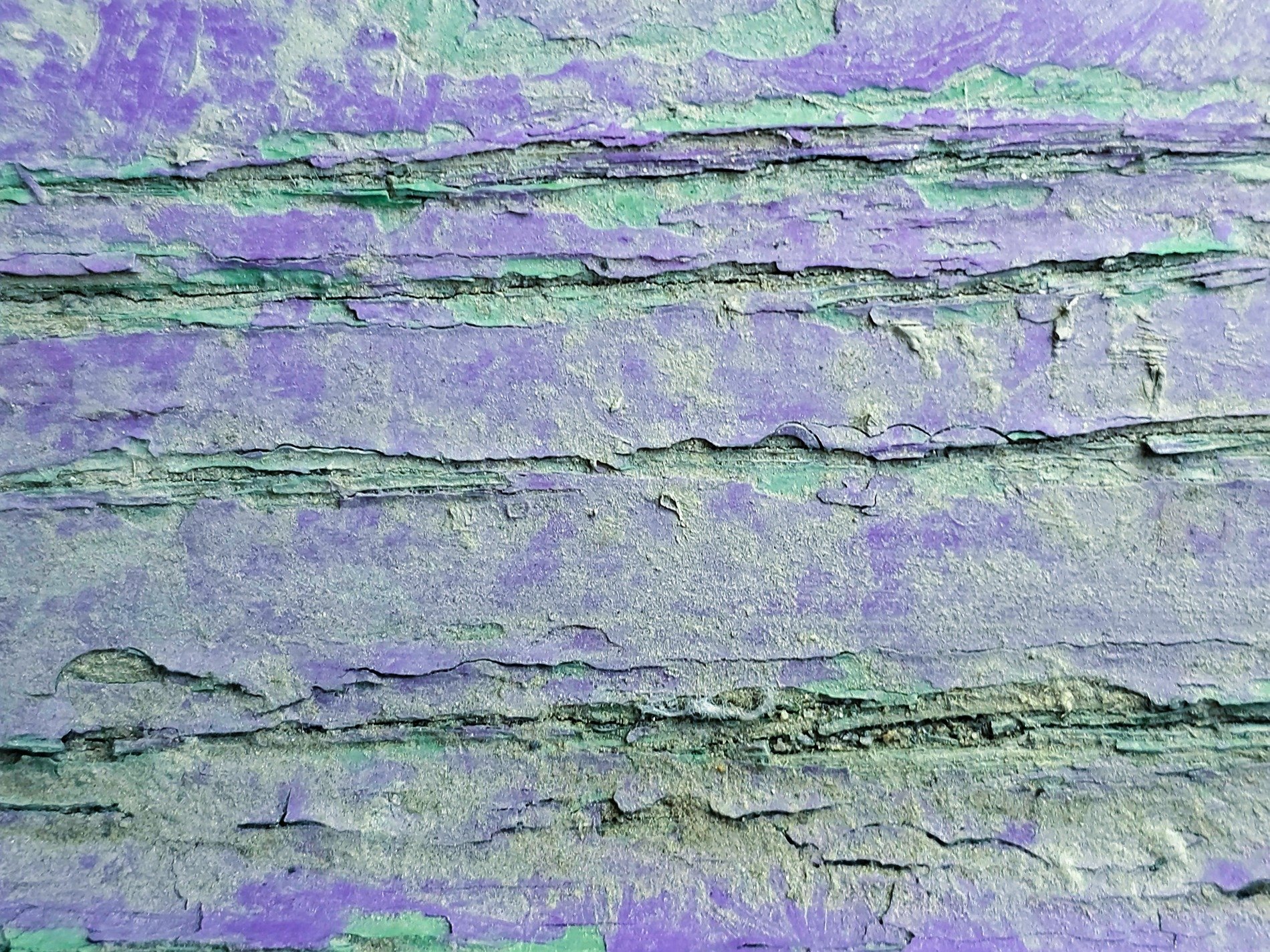 Purple layers flake, teal paint hides in the fissures, wood shows through the cracks