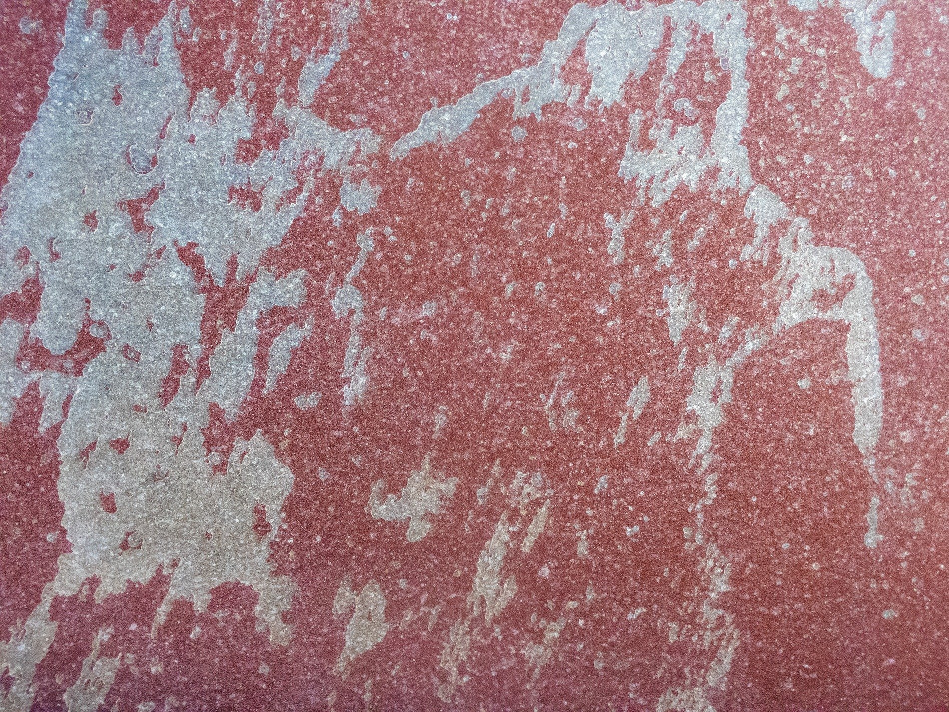Red paint fades away, white stains spread like ghostly maps, texture tells the tale
