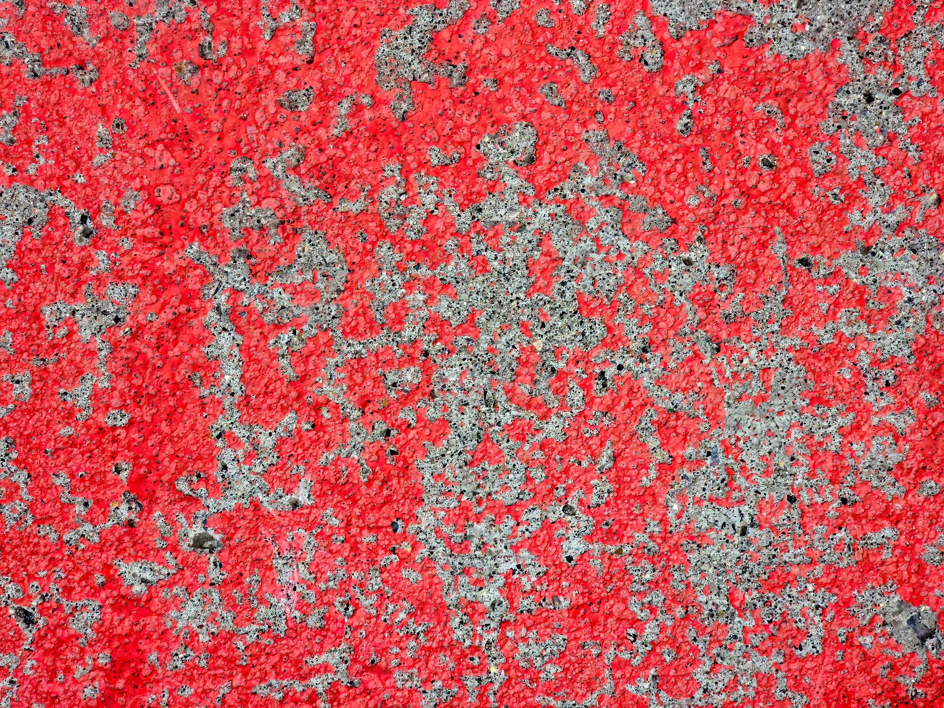 Red paint skins the stone, rough grey surface peeks between, weathered textures stay