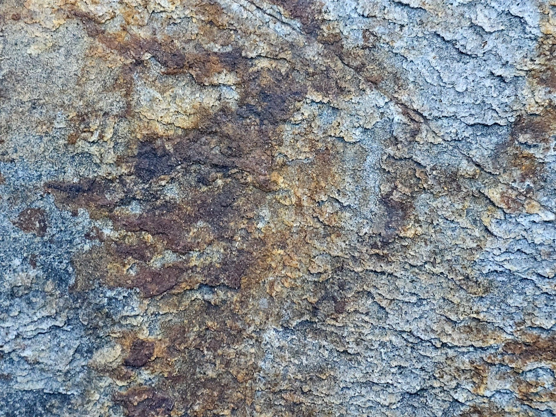 Rough layers of stone, ochre stains the ancient slate, time peels back the earth