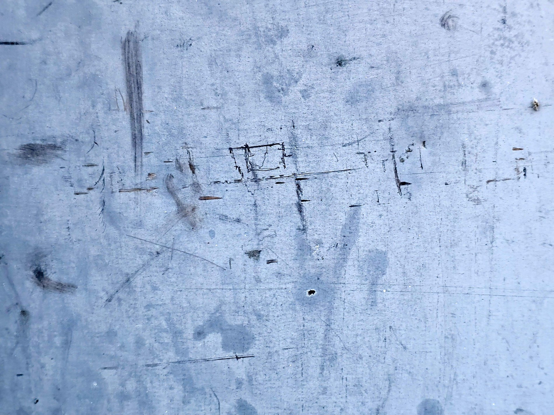 Scratched blue metal skin, dark marks dance across the field, time leaves its imprint