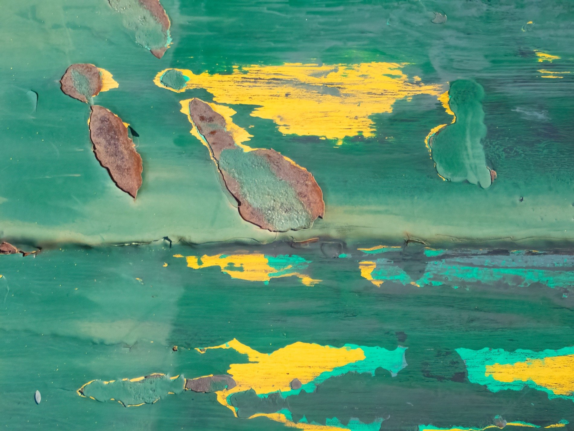 Teal paint flakes away, yellow streaks shine through the wear, rust marks time's decay