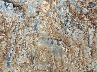 Ancient rock face scars, iron veins bleed through the grey, weathered stone endures
