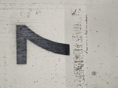 Black ink on concrete, slanted mark defines the space, grit meets painted wall