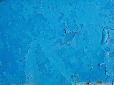 Blue layers chip away, weathered skin flakes from metal, time strips the surface