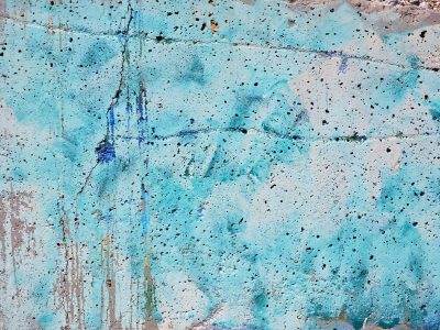 Blue paint coats the stone, jagged cracks divide the face, porous shadows wait