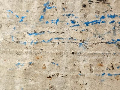 Blue paint fades away, rough concrete holds every scar, time leaves dusty marks