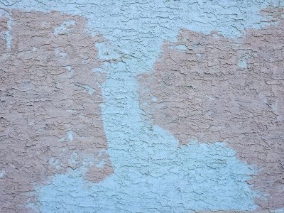 Blue paint fades away, rough pink stucco shows its grit, time wears down the wall