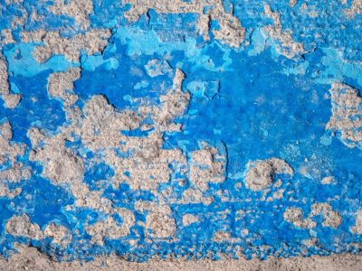 Blue paint flakes away, rough grey stone peeks through the cracks, time wears down the coat