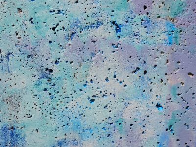 Blue paint masks the stone, pockmarks dot the rough surface, colors blend in light