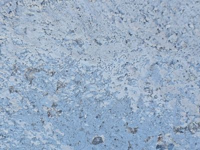 Blue paint wears away, rough concrete hides underneath, textures carved by time