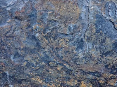 Blue shadows on stone, orange veins through the grey rock, ancient layers rest