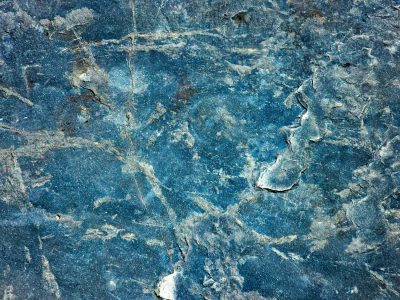 Blue stone deeply scarred, jagged veins cut through the rock, ancient surface stays