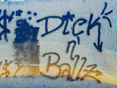 Dark ink scrawls its name, crude words on a textured pane, golden light descends