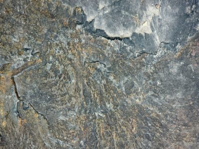Dark stone wears its age, cracks run through the ancient face, iron bleeds in time