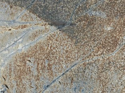 Deep fissures divide, iron stains the granite face, ancient earth reveals