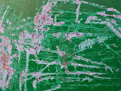 Green paint scarred and torn, lilac flakes peel from the wall, rust blooms in the cuts