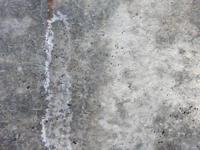 Grey cement endures, white minerals weep down slow, rough skin of the wall
