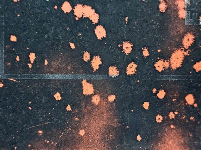 Orange spray on dark, gritty pavement holds the marks, lines fade into black