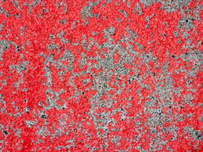 Red paint skins the stone, rough grey surface peeks between, weathered textures stay