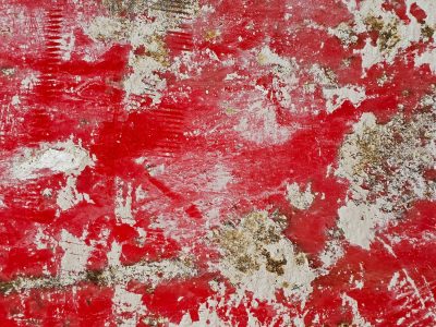 Red paint wears away, white flakes scatter on the scars, grit remains beneath