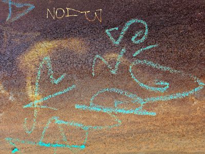 Rust claims the iron, teal chalk marks the weathered wall, decay finds a home