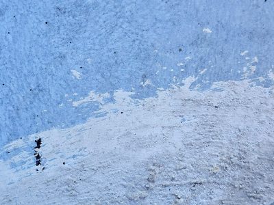 White crust climbs the wall, blue surface meets rough edges, cold texture remains