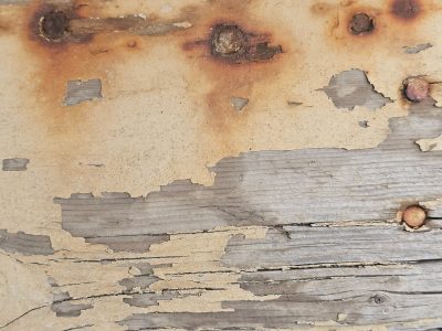 Yellow paint peels back, rusted nails hold weathered grain, time flakes the surface